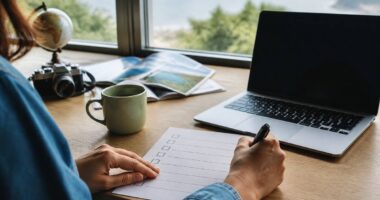 Checklist voor het vergelijken van vakanties op een bureau met laptop en reisgids