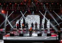 people standing on stage with lights turned on during nighttime